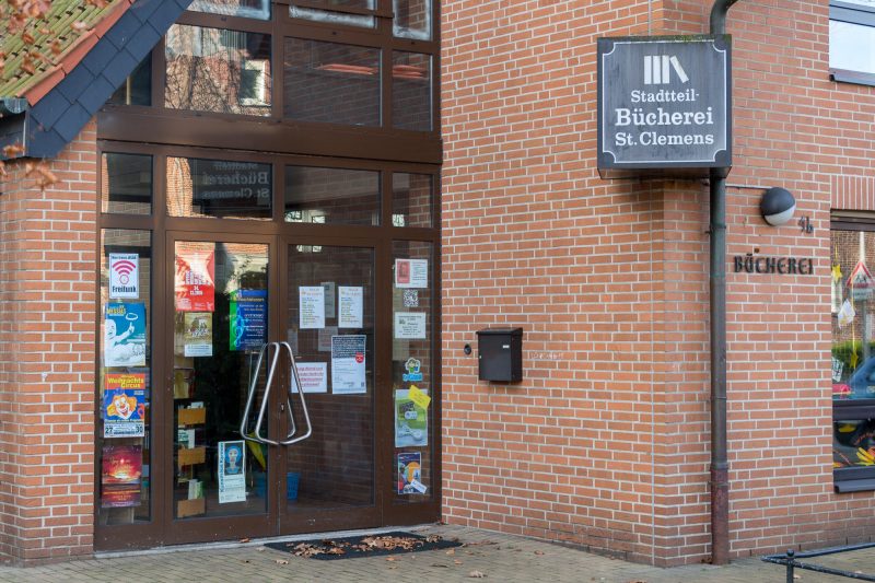 Eingang der Stadtteilbücherei St. Clemens: Backsteinfassade mit Schaufenster und Schild „Stadtteilbücherei St. Clemens“